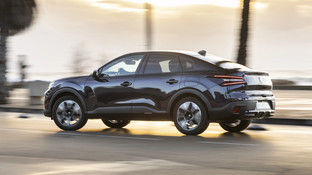 Side view of the Citroën C4 X driving along the coast at sunset, highlighting its sleek profile