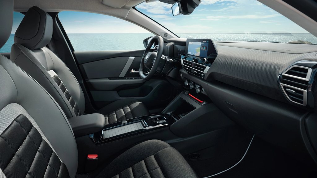 Front cabin of the Citroën C4 X with dashboard and seats shown against a seaside backdrop