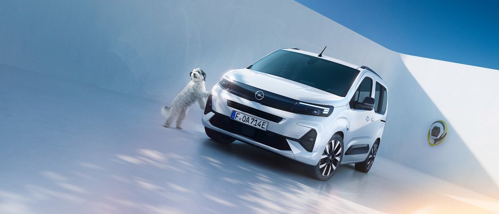 Egy fehér Opel Combo Electric egyterű első oldalnézetből és egy kutya